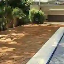 das Foto zeigt eine Poolumrandung mit schwarz verfugten Teakholz Terrassendielen