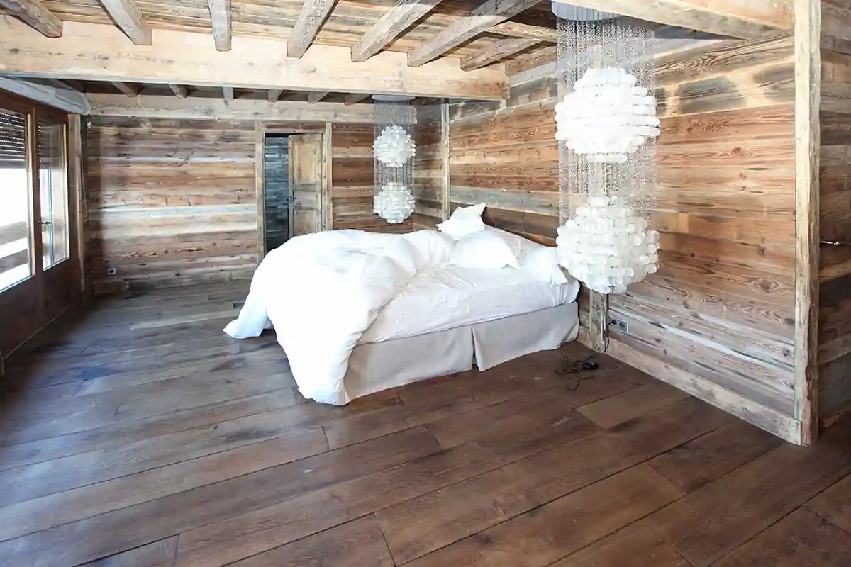 das Bild zeigt einen Raum mit Bett dessen Boden, Decke und Wand mit Holz belegt sind